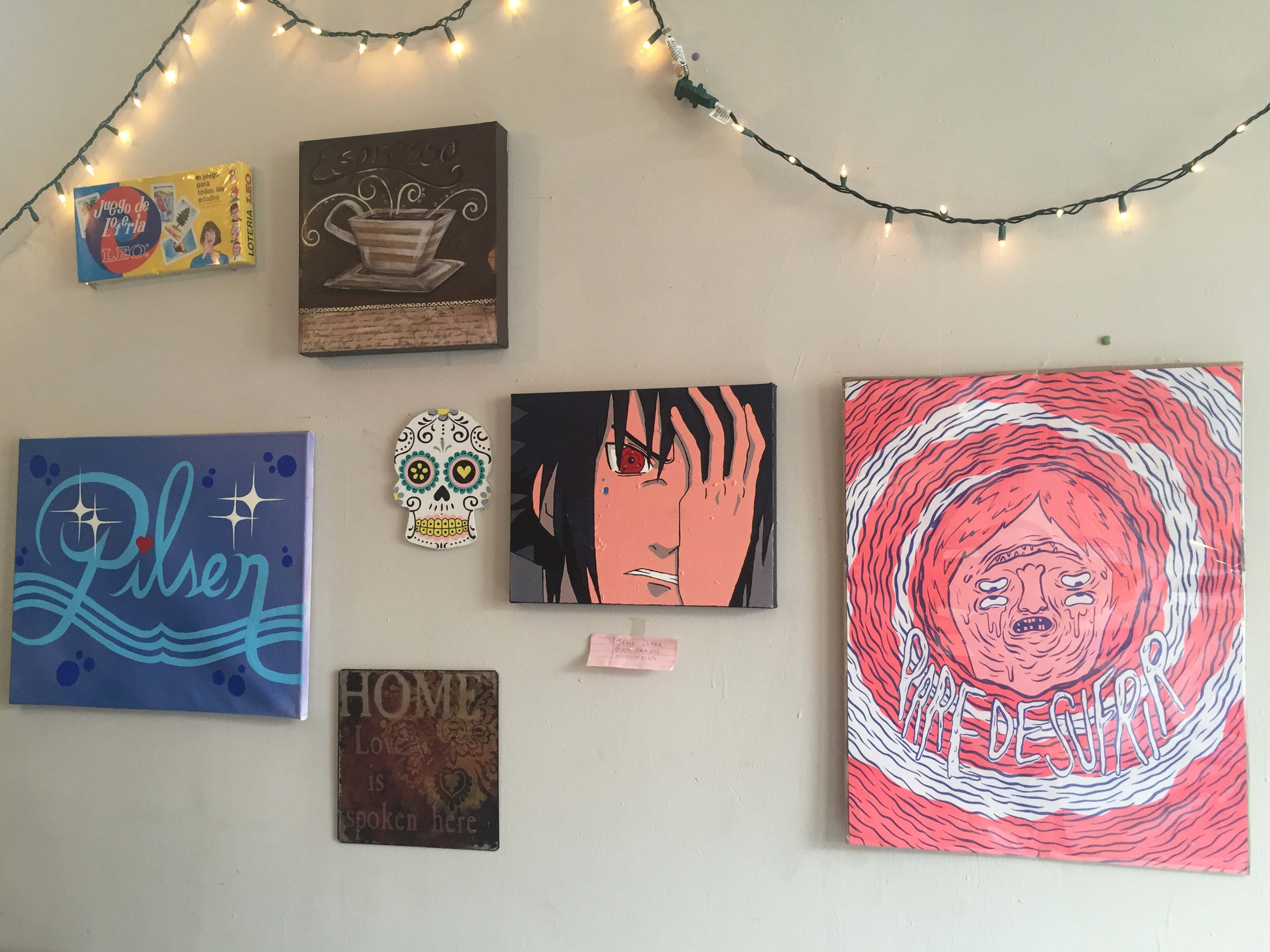 Gray wall with six paintings and christmas lights hung on it